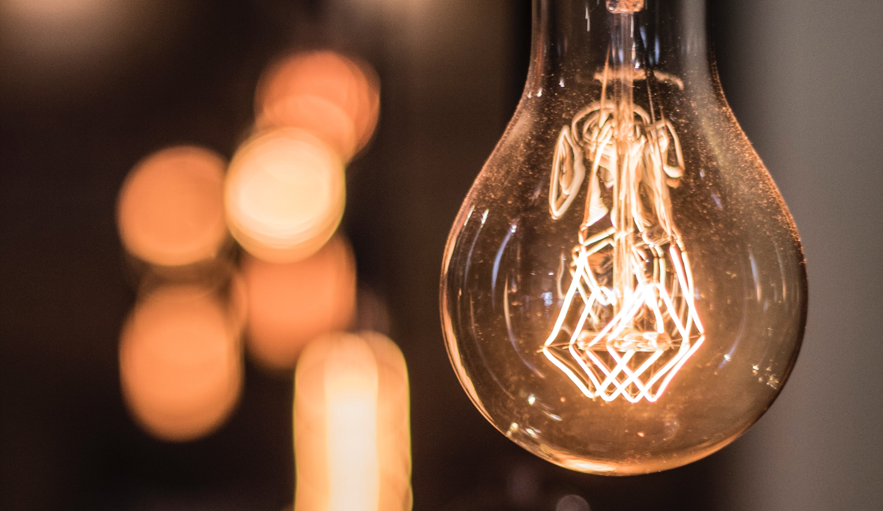 A photo of a lightbulb with a glowing filament in front of a background of other lightbulbs.
